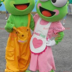 2 maskoti zelených žab v barevném oblečení