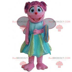 Mascota de hada rosa sonriente con un vestido colorido -
