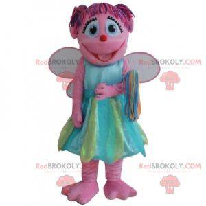 Glimlachende roze fee mascotte met een kleurrijke jurk -