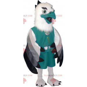 Biało-czarna szara maskotka sępa ubrana na zielono -