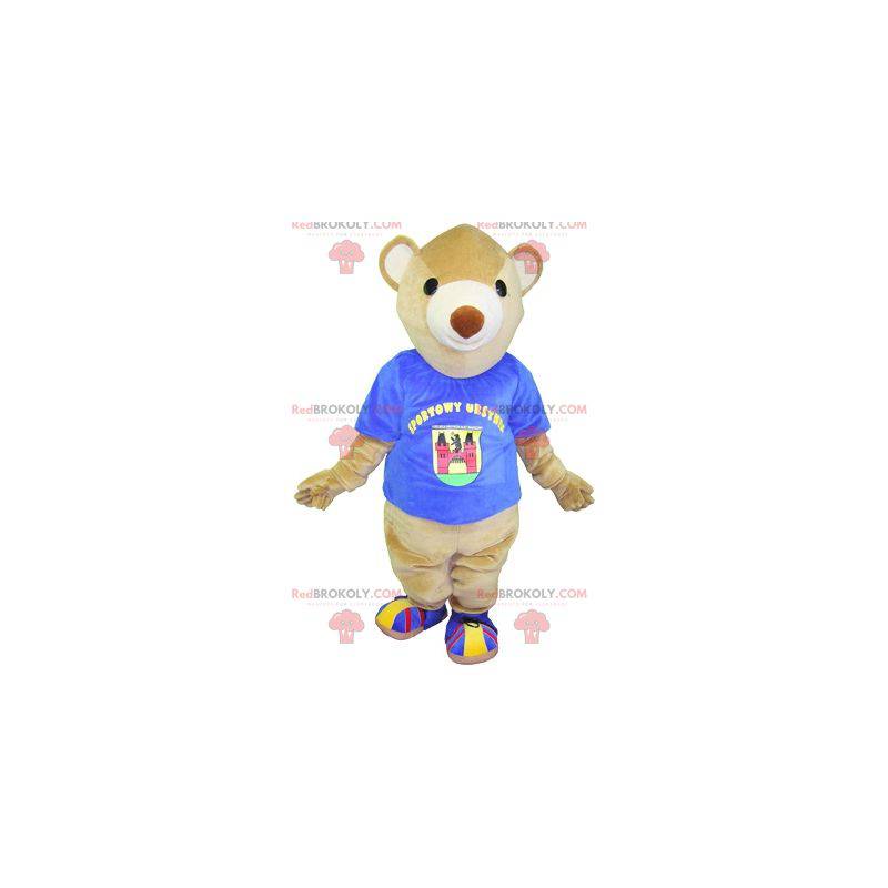 Beige Bär Maskottchen mit einem blauen T-Shirt. Teddybär