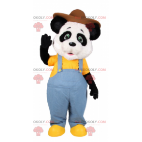 Mascota de panda con mono azul y sombrero marrón -