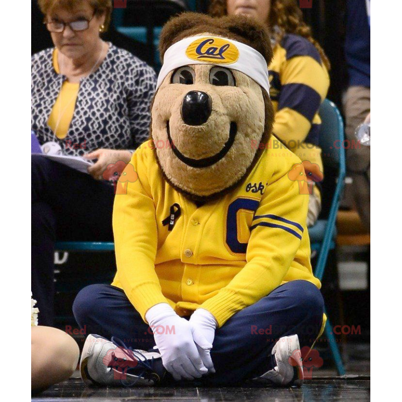 Medvěd hnědý maskot v žluté a modré sportovní oblečení -