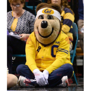 Mascotte d'ours brun en tenue de sport jaune et bleue -