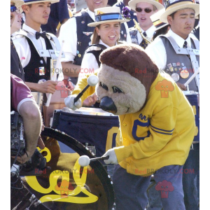 Mascotte orso bruno in abbigliamento sportivo giallo e blu -