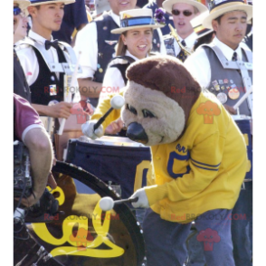 Mascotte d'ours brun en tenue de sport jaune et bleue -