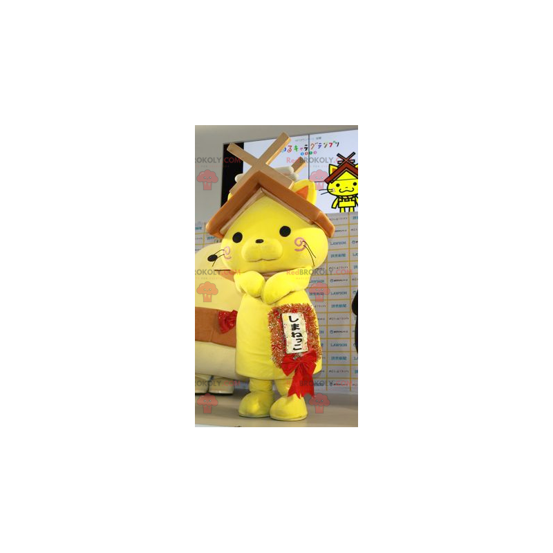 Mascote gato amarelo com um telhado de casa na cabeça -