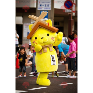 Mascote gato amarelo com um telhado de casa na cabeça -