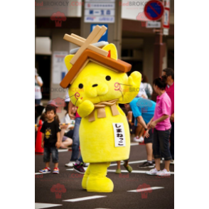 Mascote gato amarelo com um telhado de casa na cabeça -