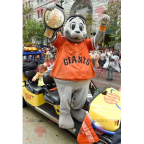 Mascote leão marinho cinza com uma camiseta laranja -