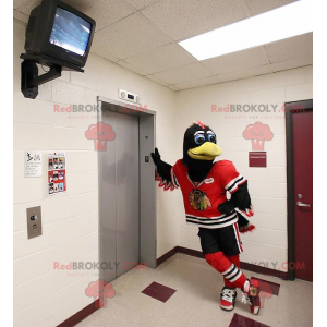 Mascotte d'oiseau noir et blanc avec une tenue de sport rouge -