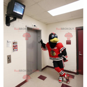 Mascotte d'oiseau noir et blanc avec une tenue de sport rouge -