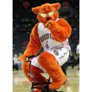 Mascotte d'ours orange avec des lunettes en tenue de basketteur