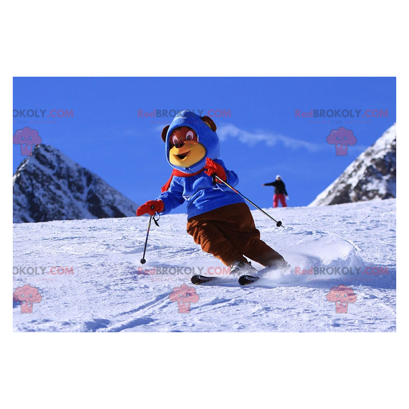 Brązowy i żółty niedźwiedź maskotka w stroju narciarskim.