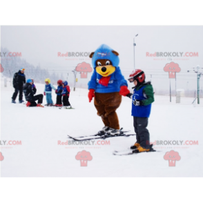 Brun og gul bjørnemaskot i skiantrekk. Vinterbamse -