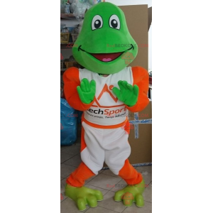 Maskotka zielona żaba ubrana w biało-pomarańczowy strój -
