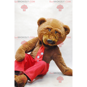 Mascotte d'ours brun avec une cravate et un pantalon rouge -