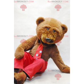 Mascotte d'ours brun avec une cravate et un pantalon rouge -