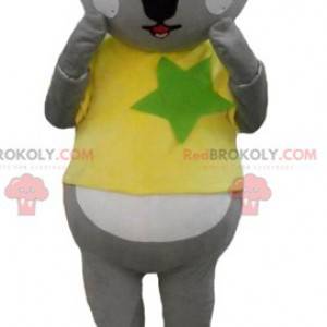 Mascota koala gris y blanco con una camiseta amarilla y verde -