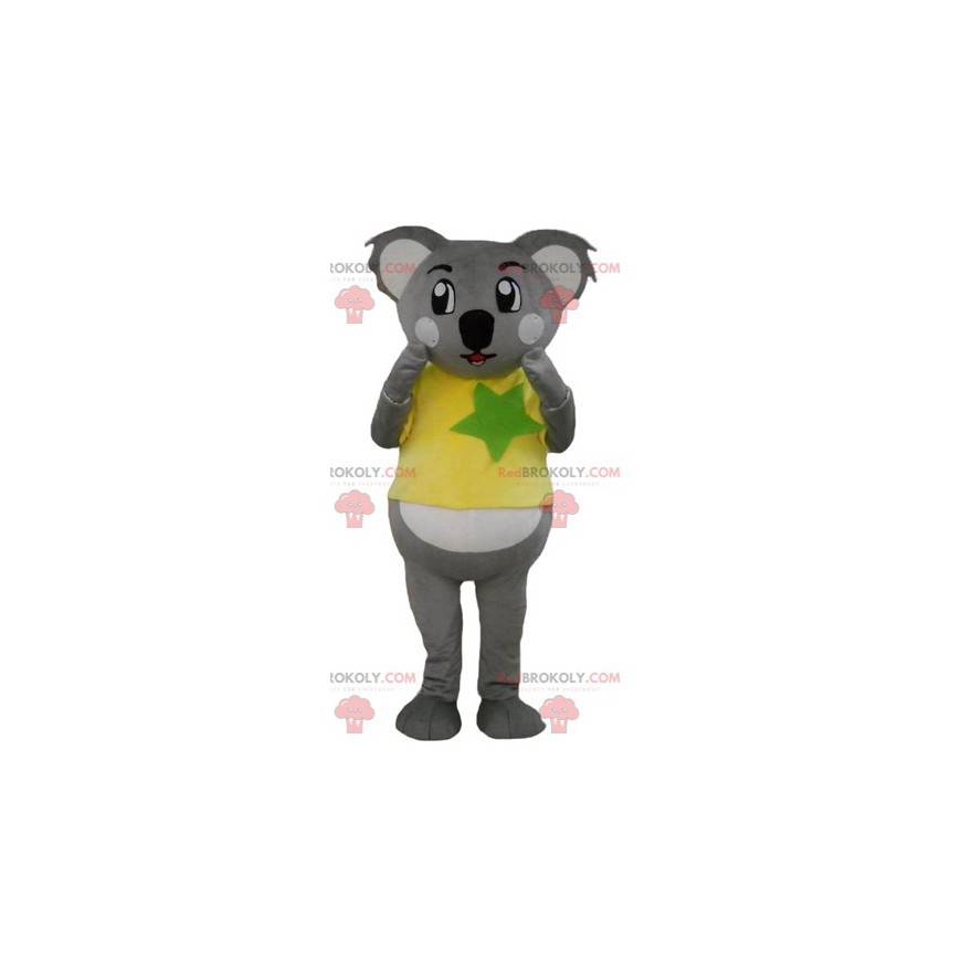 Grå og hvit koala maskot med en gul og grønn t-skjorte -