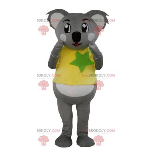 Mascotte koala grigio e bianco con una maglietta gialla e verde