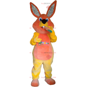 Mascote coelho laranja e amarelo com uma cenoura -