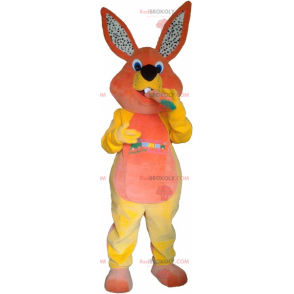 Mascote coelho laranja e amarelo com uma cenoura -