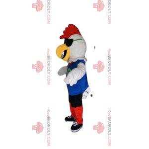 Biała maskotka kurczaka w czerwonej i niebieskiej odzieży sportowej