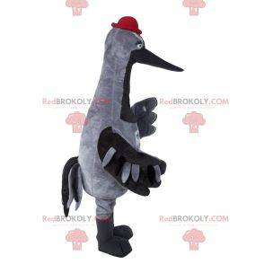 Mascota de la cigüeña gris con un sombrero rojo