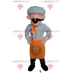 Maskotka szefa kuchni w białym kapeluszu i pomarańczowym fartuchu.