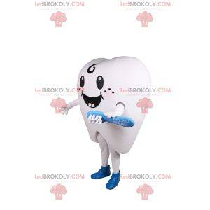 Smilende hvid tand maskot og blå tandbørste