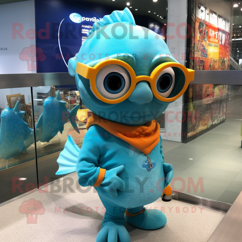 Turquoise Goldfish mascot costume character dressed with a Graphic Tee and Eyeglasses Turquoise Goldfish mascot costume character dressed with a Graphic Tee and Eyeglasses