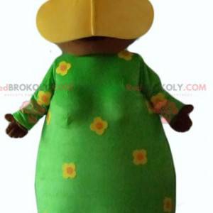 Afrikansk kvinnamaskot med en grön blommig klänning -