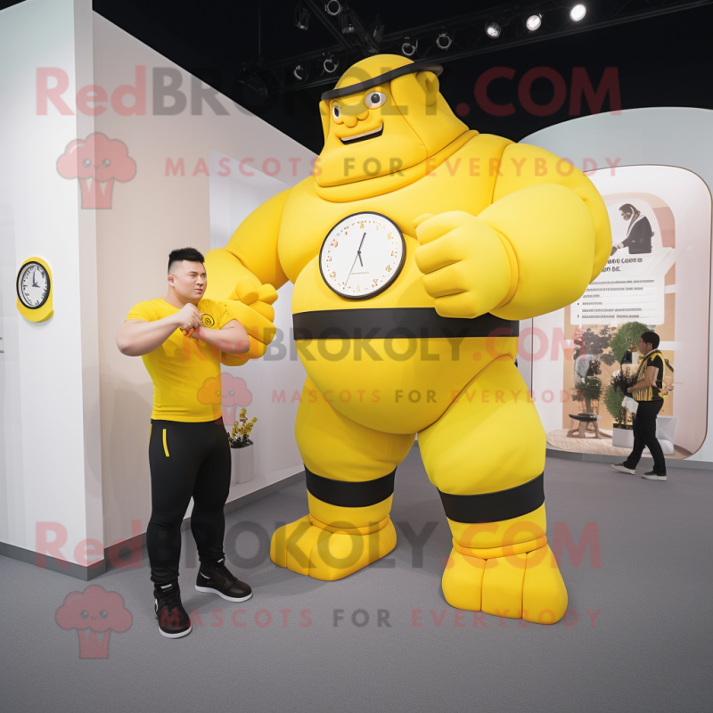 Yellow Strongman mascot costume character dressed with a T-Shirt and Smartwatches Yellow Strongman mascot costume character dressed with a T-Shirt and Smartwatches