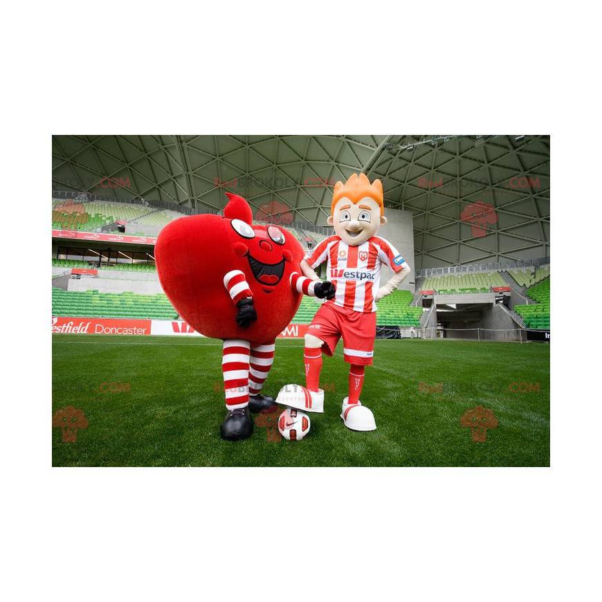 2 mascotes, um coração vermelho gigante e um jogador de futebol