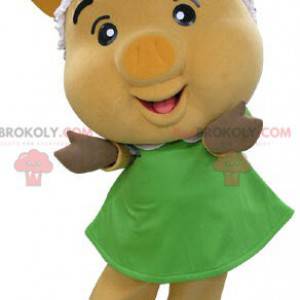 Gelbes Schweinemaskottchen mit einem grünen Kleid -