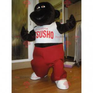 Mascota gorila marrón oscuro con un traje rojo y blanco -