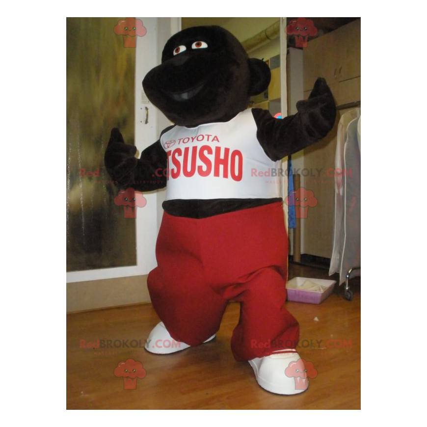 Mascota gorila marrón oscuro con un traje rojo y blanco -