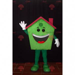 Mascotte de maison verte souriante avec un toit rouge -