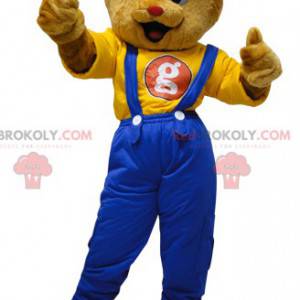 Mascotte teddybeer gekleed in een overall met een pet -