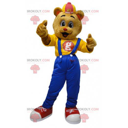 Mascotte teddybeer gekleed in een overall met een pet -