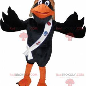 Mascota de cuervo negro y naranja con casco de piloto. -