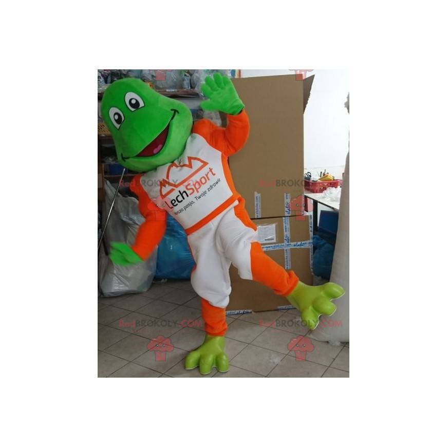 Maskotka zielona żaba ubrana w biało-pomarańczowy strój -