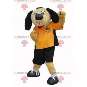 Mascotte de chien beige et noir en tenue de footballeur -