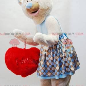 Beige nallebjörnmaskot med en klänning och ett rött hjärta -