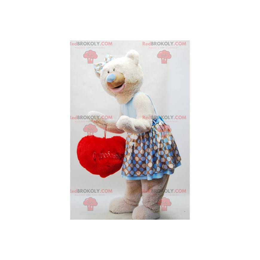 Beige nallebjörnmaskot med en klänning och ett rött hjärta -