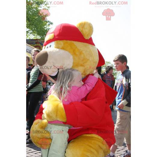 Mascotte de gros ours jaune et rouge avec une casquette -