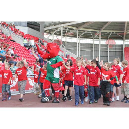 Rotes Drachenmaskottchen in grüner Sportbekleidung -