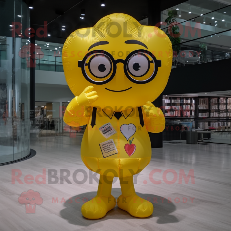 Yellow Heart Shaped Balloons mascot costume character dressed with a Romper and Reading glasses Yellow Heart Shaped Balloons mascot costume character dressed with a Romper and Reading glasses